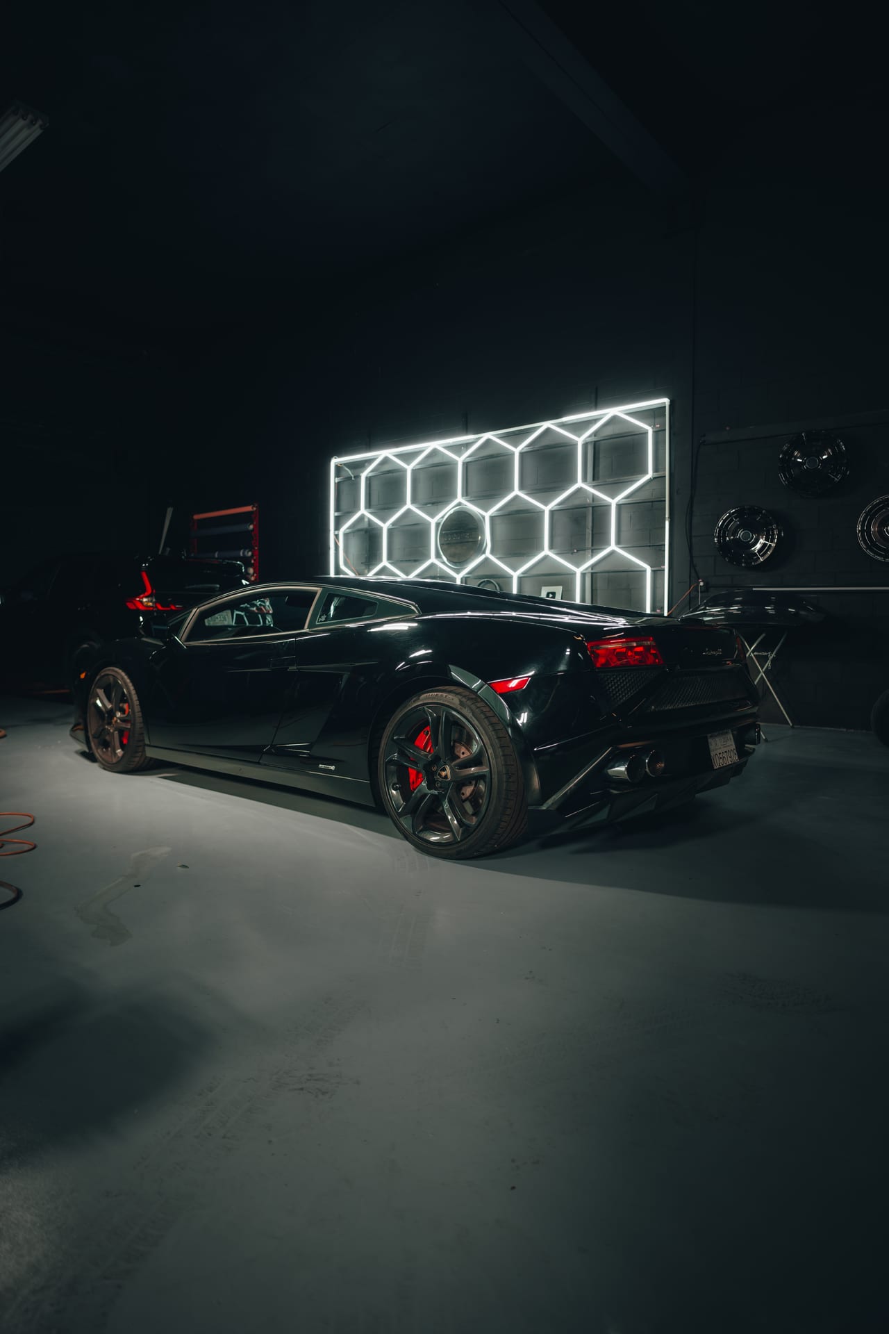 Black Lamborghini Gallardo backlit by hexagonal LED panels